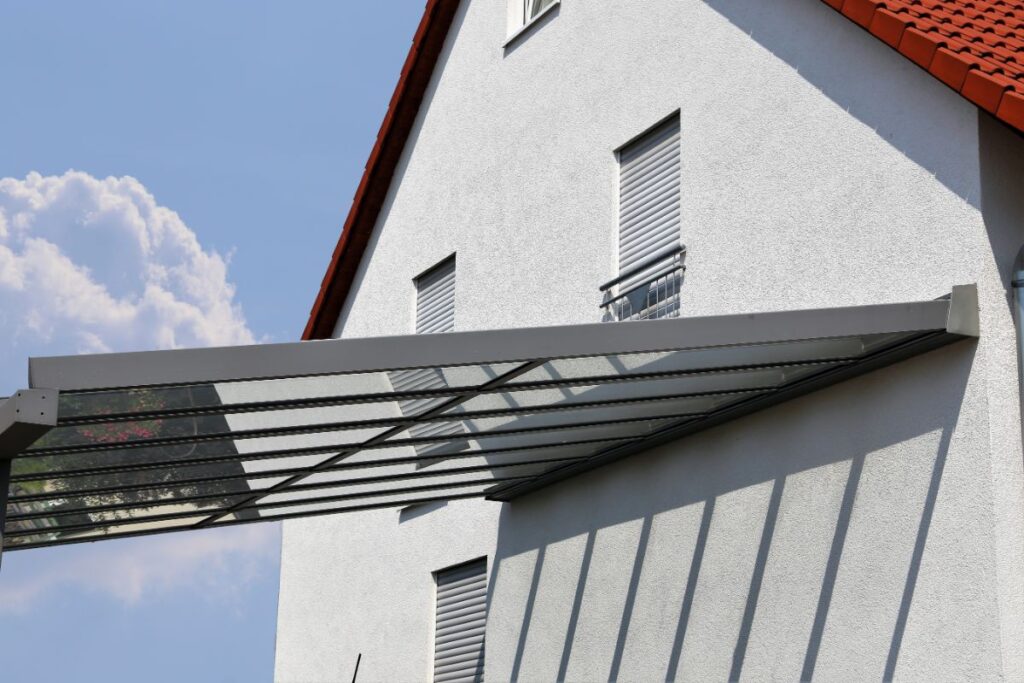 Ein hochwertiges Terrassendach aus Glas schützt die moderne Terrasse vor Regen.
